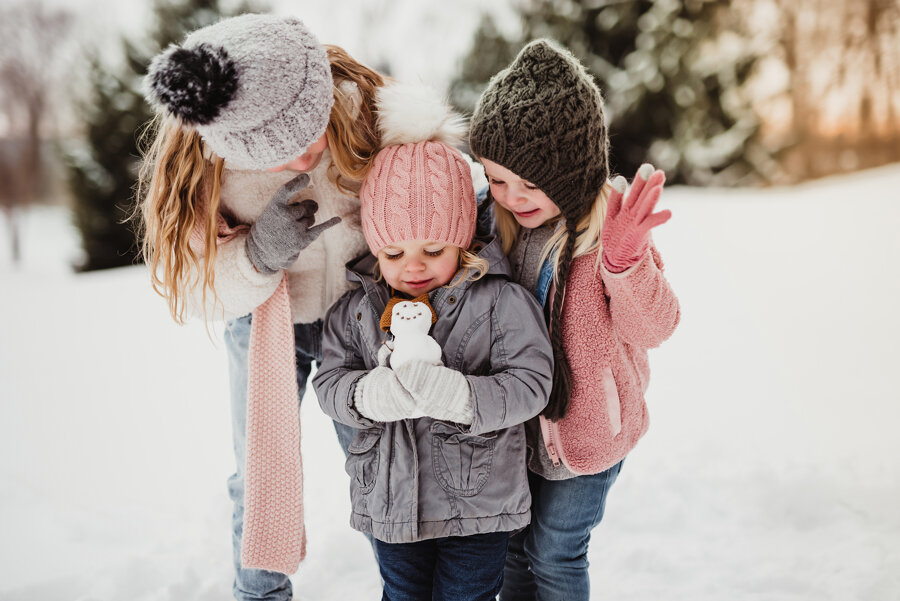 little girls holding a snowman during their family photo session with family photographer Kelly McPhail