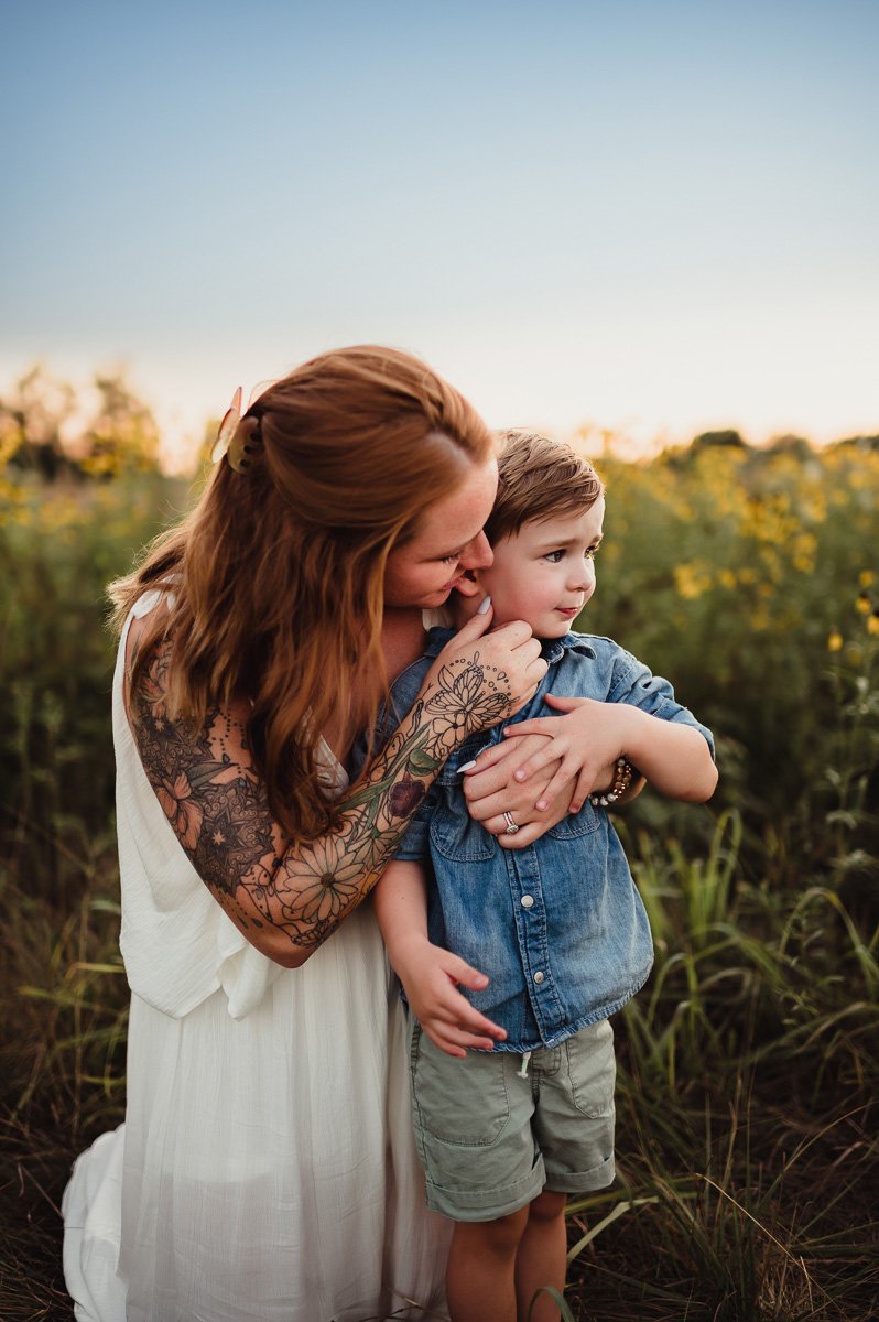 mom caressing young son's cheek in midwest summer field