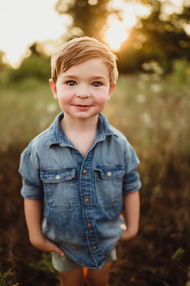 cute toddler in denim shirt smiling in midwest summer field