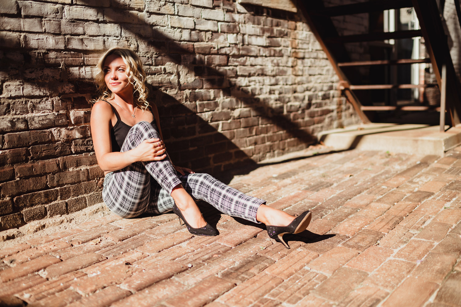 senior girl sitting and leaning on brick wall in downtown Lafayette, IN