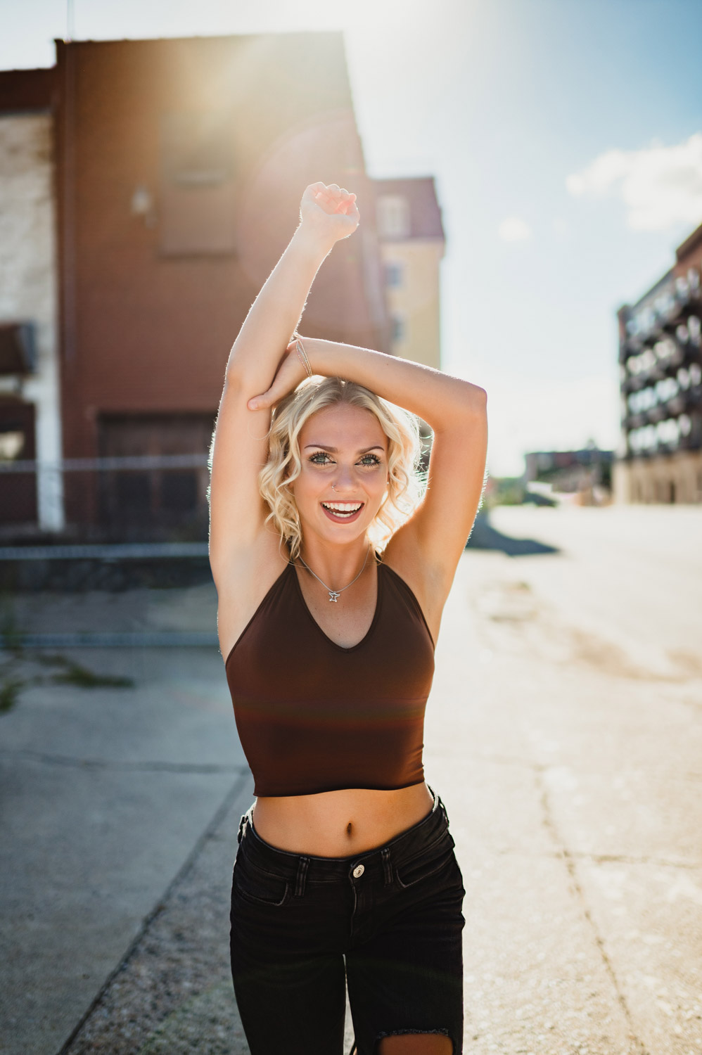 senior girl posting with one arm in the air in an urban setting
