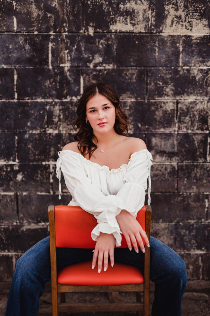 Capture the Real You: A Senior Photo Session Experience in Greensboro-senior photo session in Greensboro Bold urban senior photo session in Greensboro NC. Confident pose in front of a textured black wall with modern, artistic vibe.