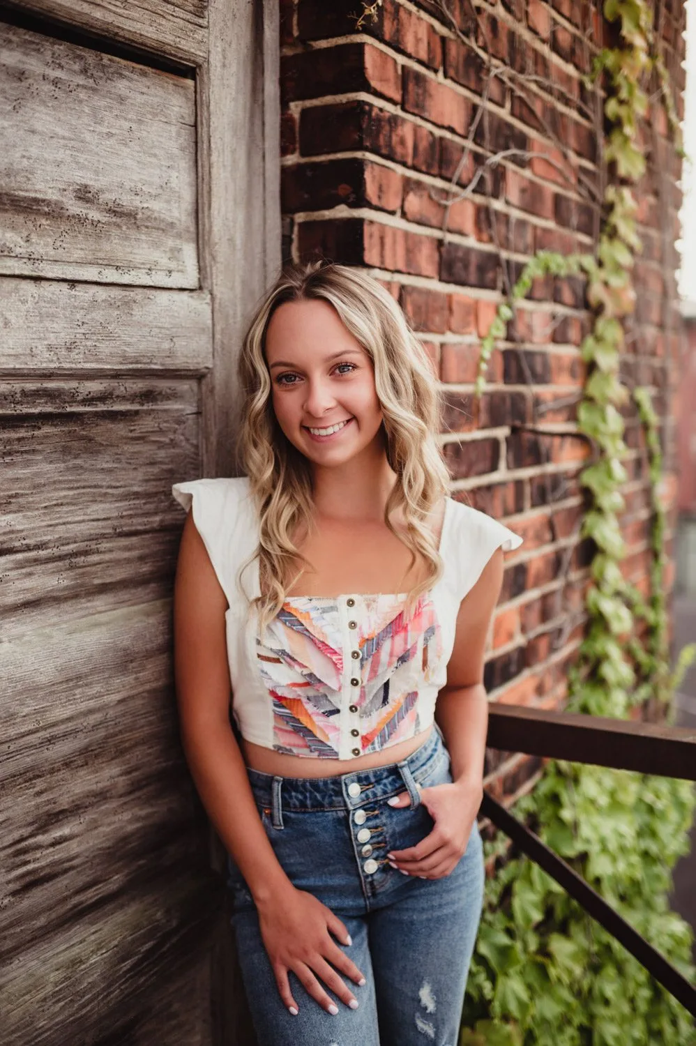 Capture the Real You: A Senior Photo Session Experience in Greensboro-senior photo session in Greensboro High school senior girl posing in downtown Greensboro NC for her senior photography session. Urban backdrop with warm, rustic textures.