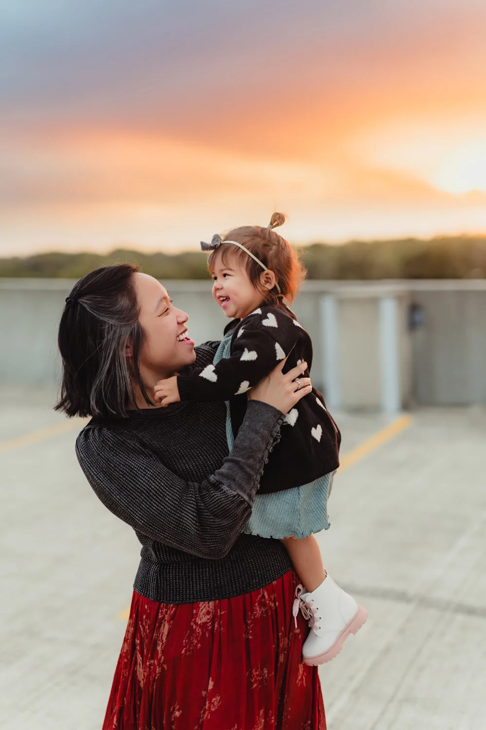 mom and young daughter embracing at sunset on top of urban parking garage