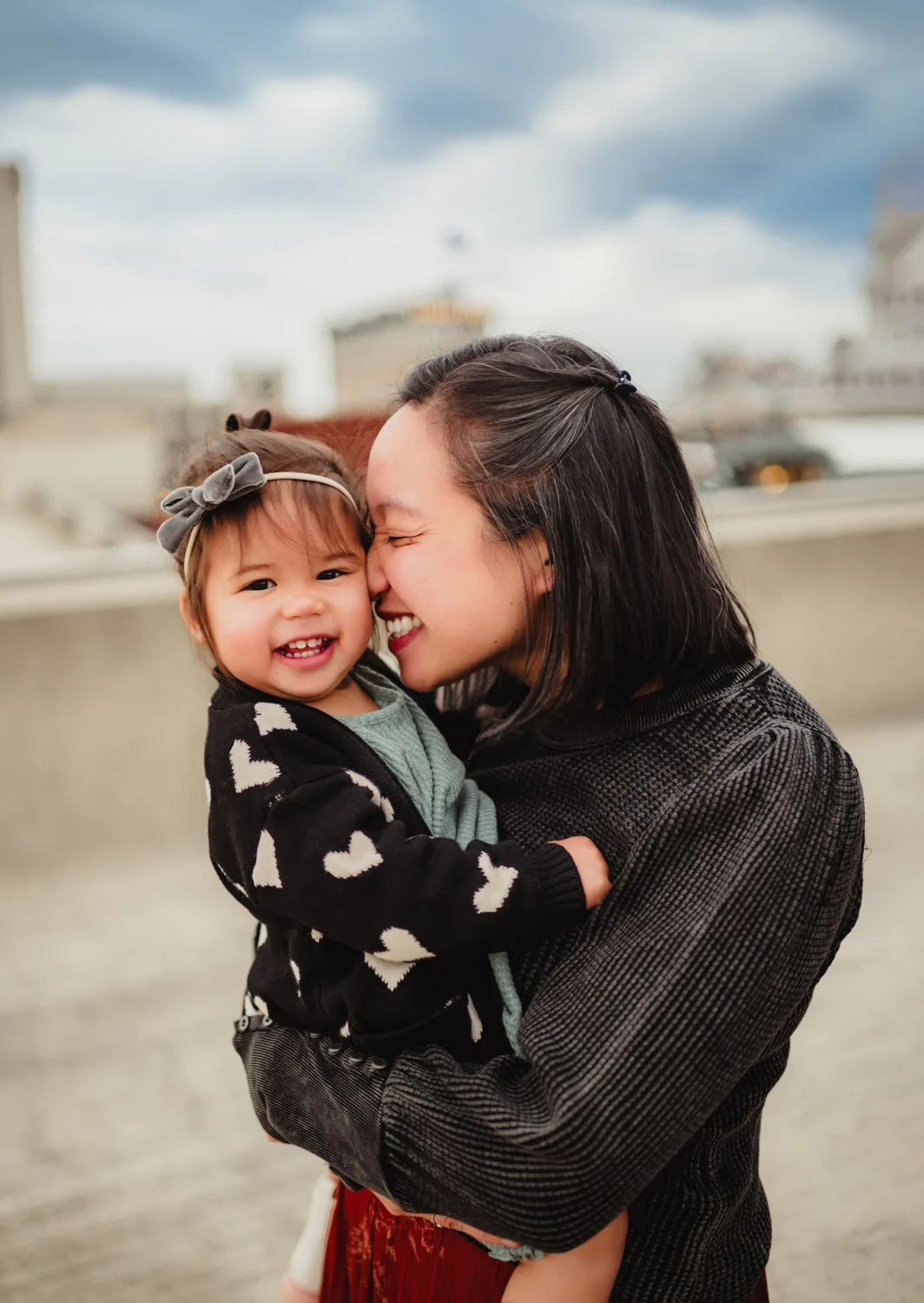 mom snuggling young daughter on top of parking garage