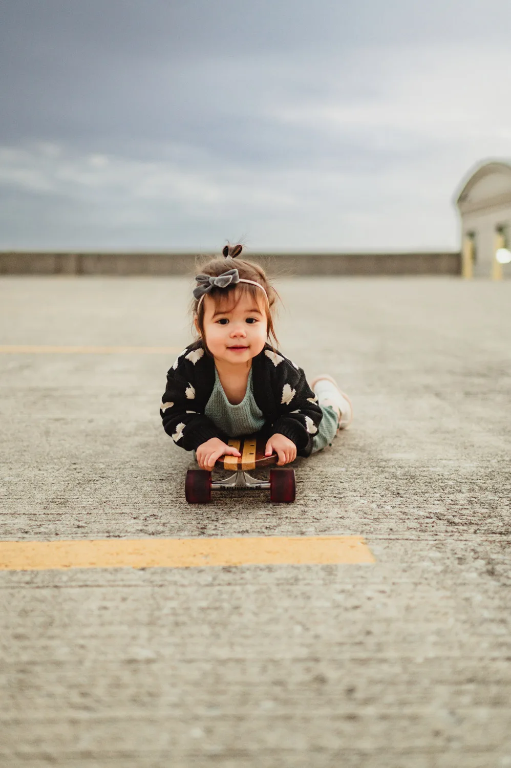 toddler laying on skateboard in parking lot