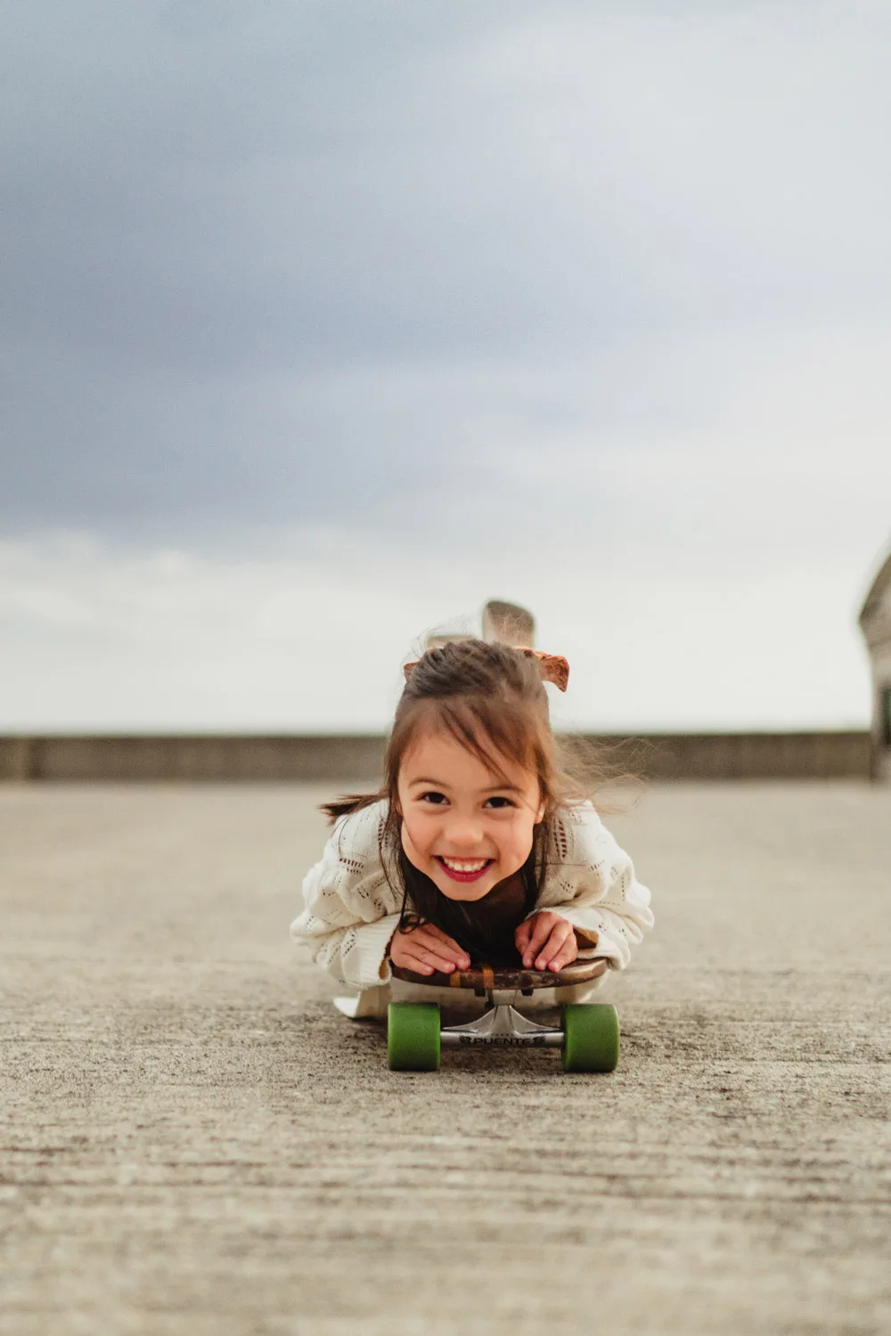 toddler laying on skateboard in concrete parking lot