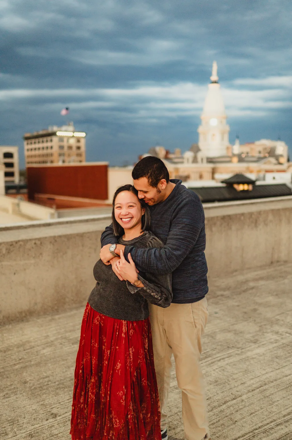 couple embracing on top of parking garage with downtown in background