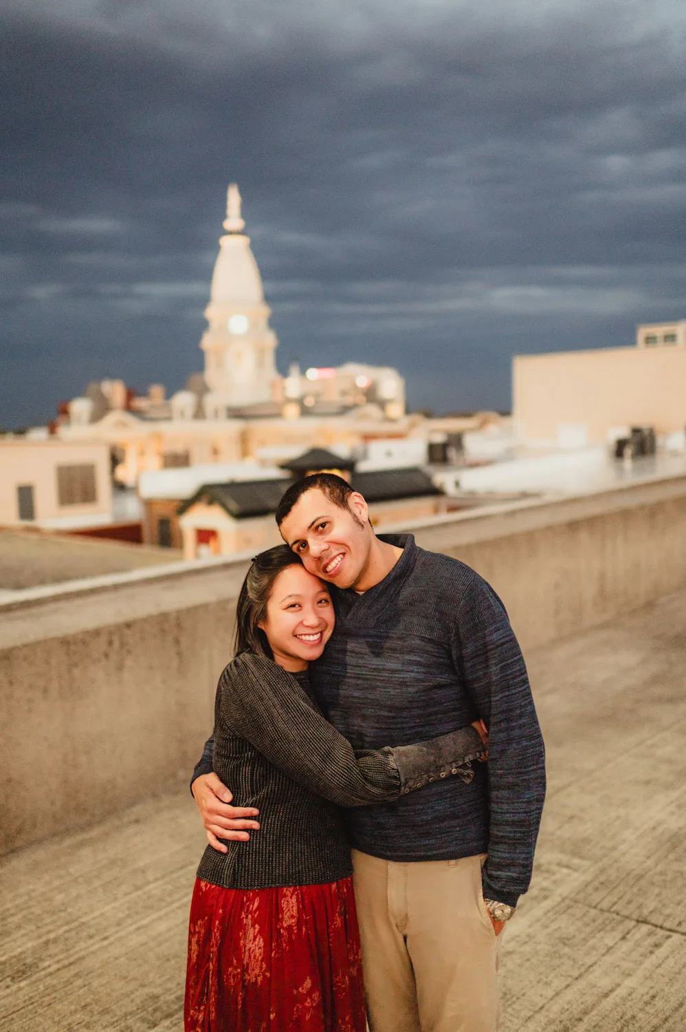 couple embracing on top of parking garage with county government building in background