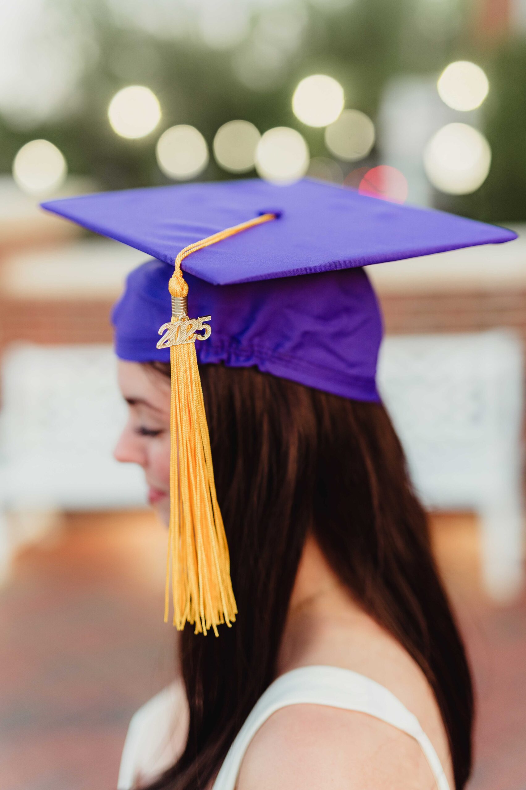 College Grad Photos: 5 Must-Know Tips for an Unforgettable Photo Session Close-up of a college graduate wearing a purple cap with a gold tassel and 2025 charm, with soft background bokeh.