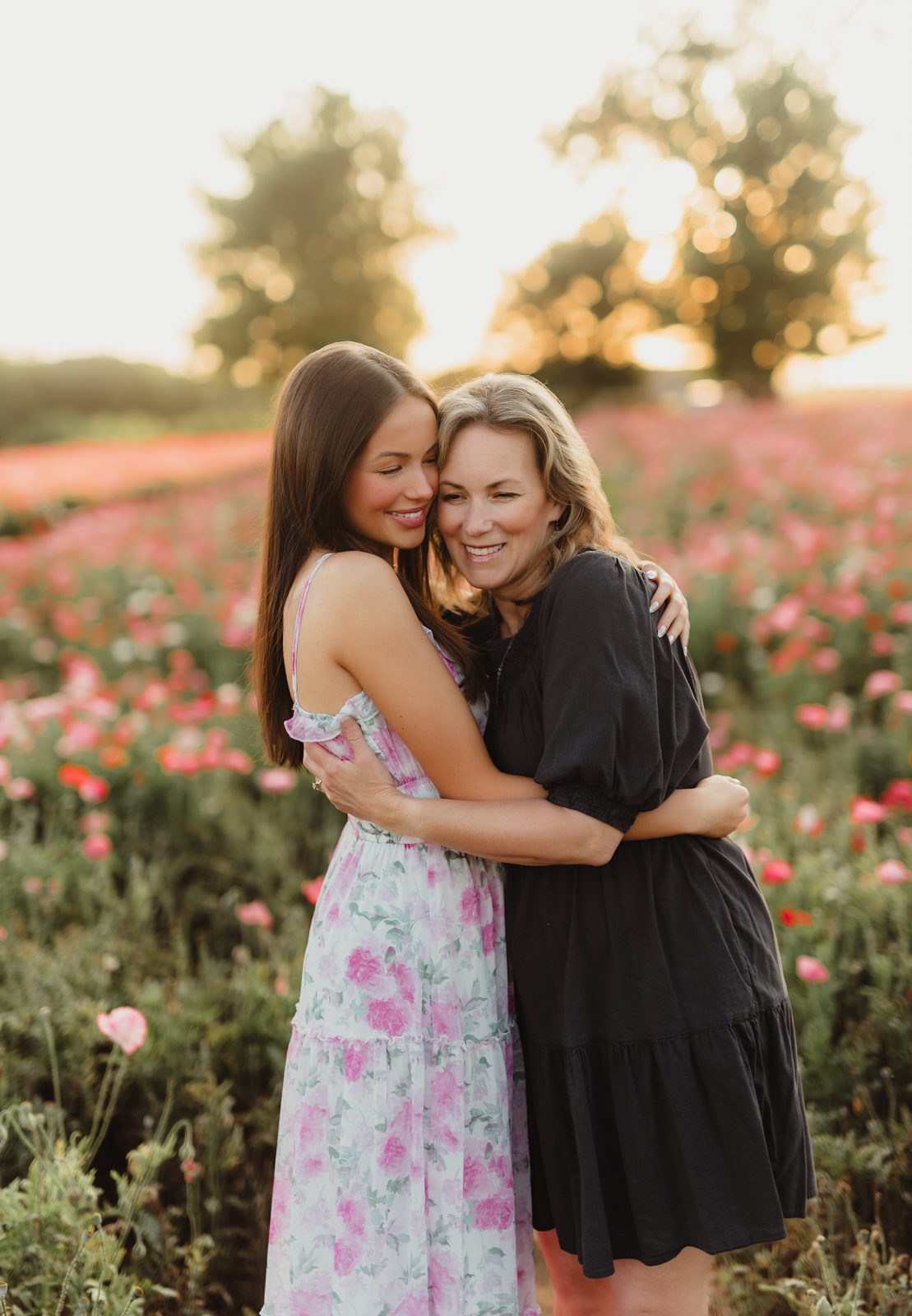 Wildflowers at Golden Hour: Genna’s Senior Session | Greensboro Senior Photographer-Greensboro Senior Photographer Sweet mother-daughter hug in a blooming wildflower field at sunset during senior photo session.