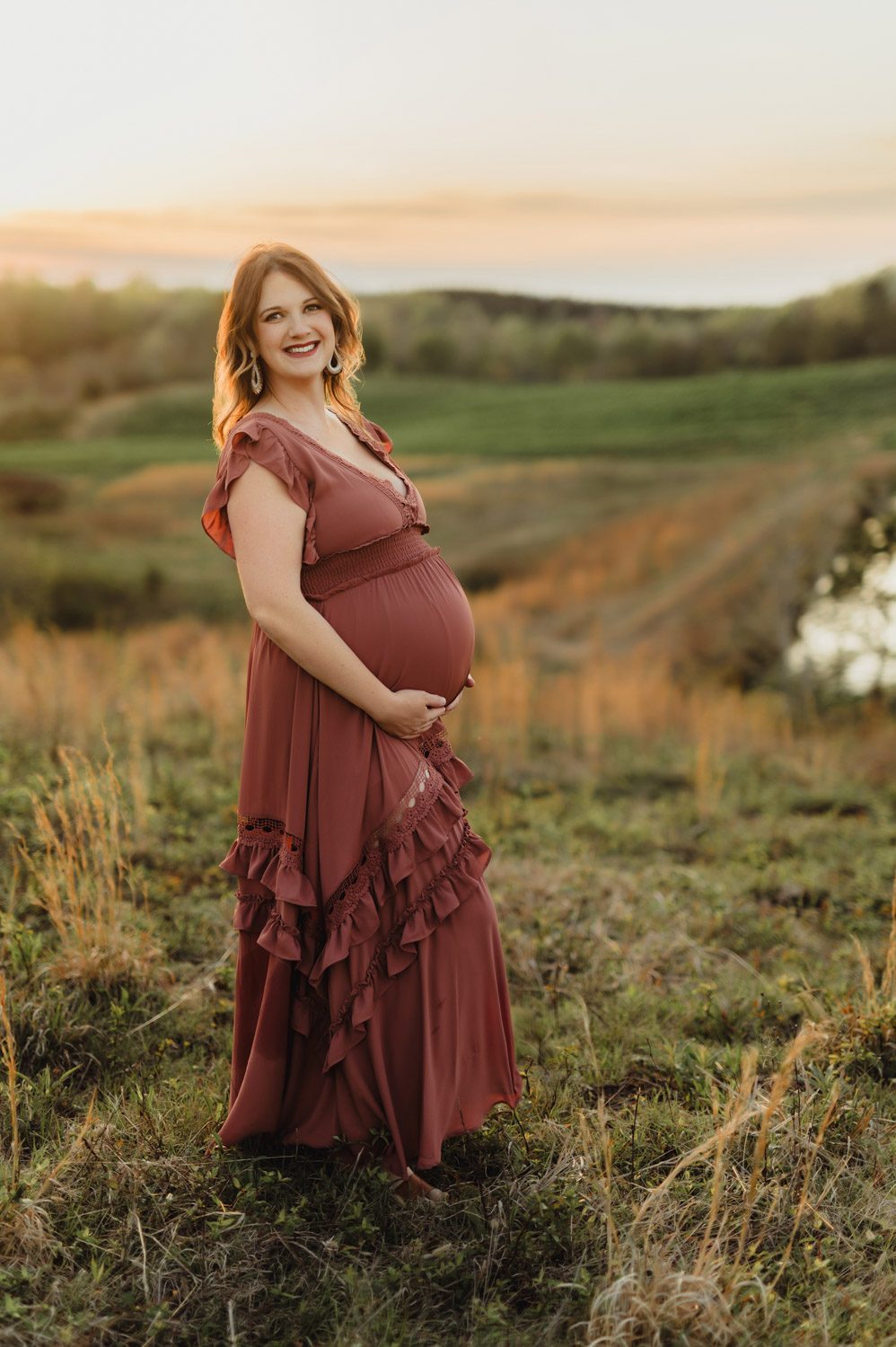 Expecting Baby #2: Golden Hour Maternity Photos in Greensboro-Greensboro maternity photos Expecting mother smiling in a flowing dress during golden hour maternity session in a Greensboro field