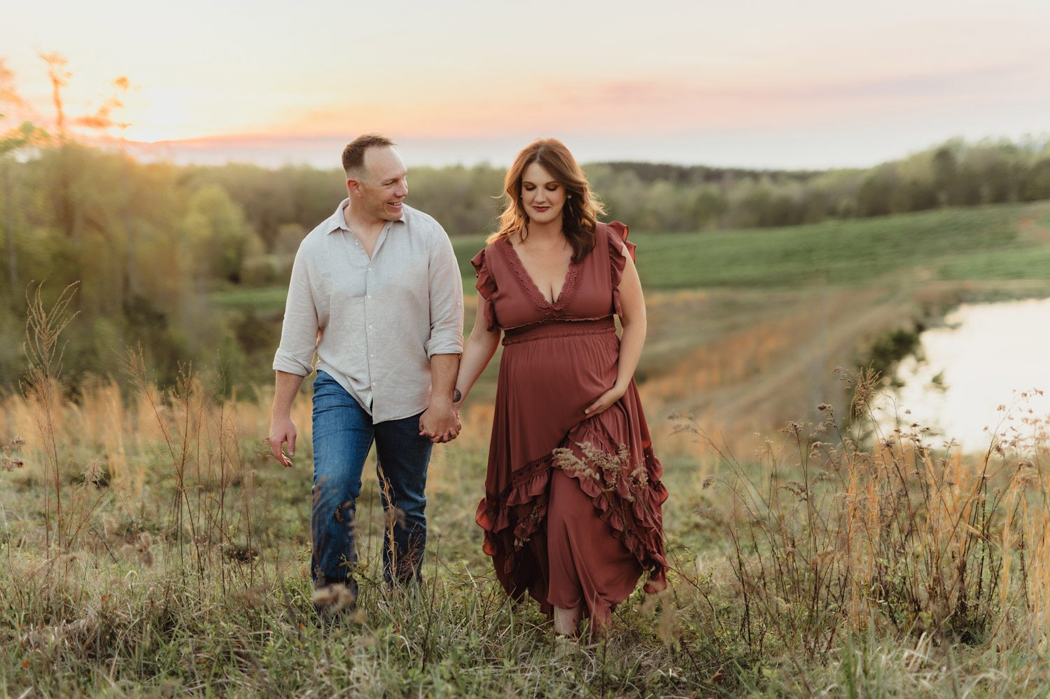 Expecting Baby #2: Golden Hour Maternity Photos in Greensboro-Greensboro maternity photos Expecting couple walking hand in hand at sunset during a maternity photo session near Greensboro, NC