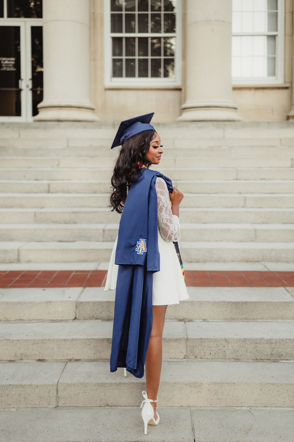 NC A&T Graduation Photos - Victoria’s Golden Hour Session-NC A&T graduation photos NC A&T graduation photo of a young woman in cap and gown standing on the steps of the historic Dudley Memorial Building at golden hour.