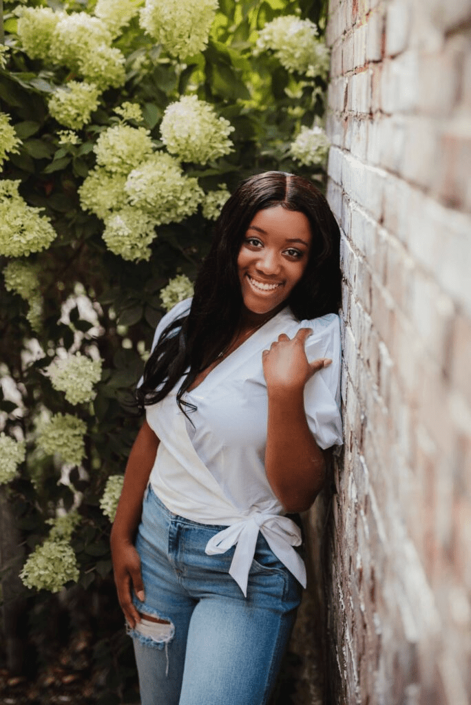 Capture the Real You: A Senior Photo Session Experience in Greensboro-senior photo session in Greensboro Senior photo session in Greensboro NC with a high school senior girl posing in front of blooming hydrangeas and brick for a vibrant, natural look.