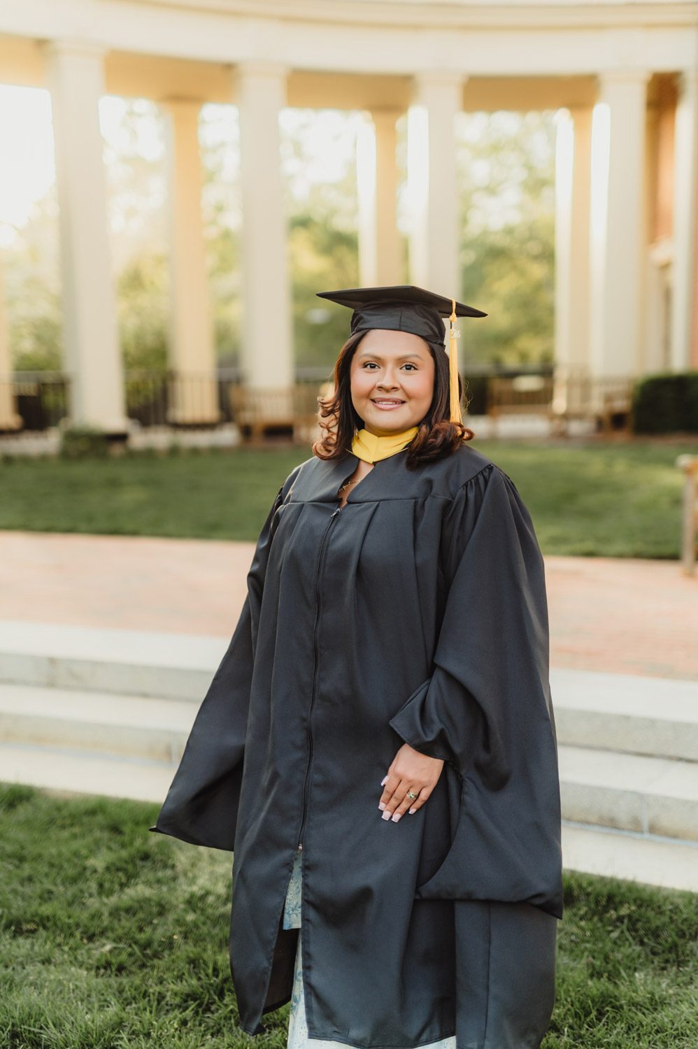 Wake Forest Graduation Photos | Celebrating Aris’s Master’s Degree-Wake Forest graduation photos Portrait of Wake Forest graduate in black cap and gown at iconic campus architecture during golden hour