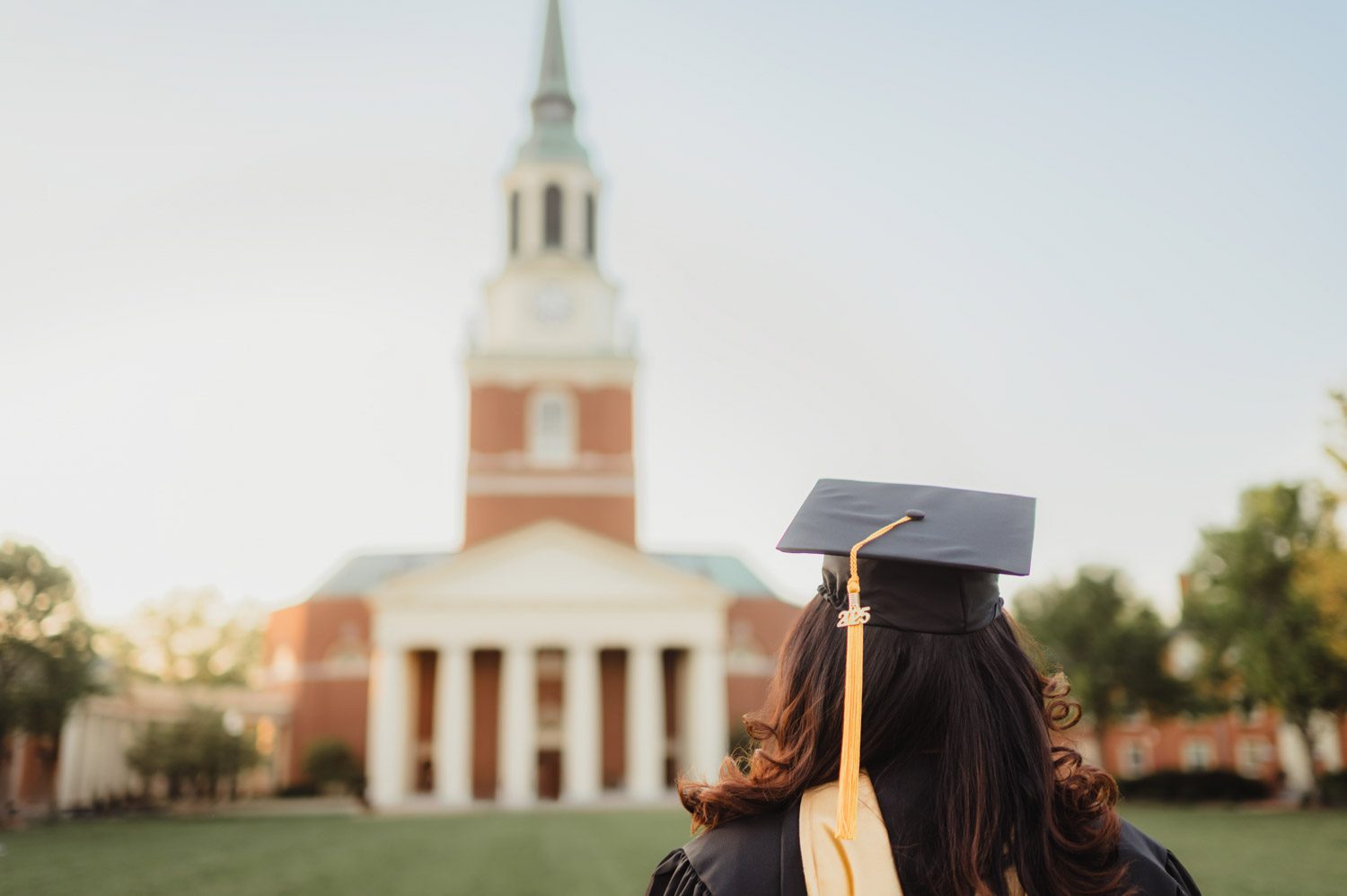Wake Forest Graduation Photos | Celebrating Aris’s Master’s Degree-Wake Forest graduation photos Wake Forest graduation photo with student in cap and gown facing Wait Chapel at sunset