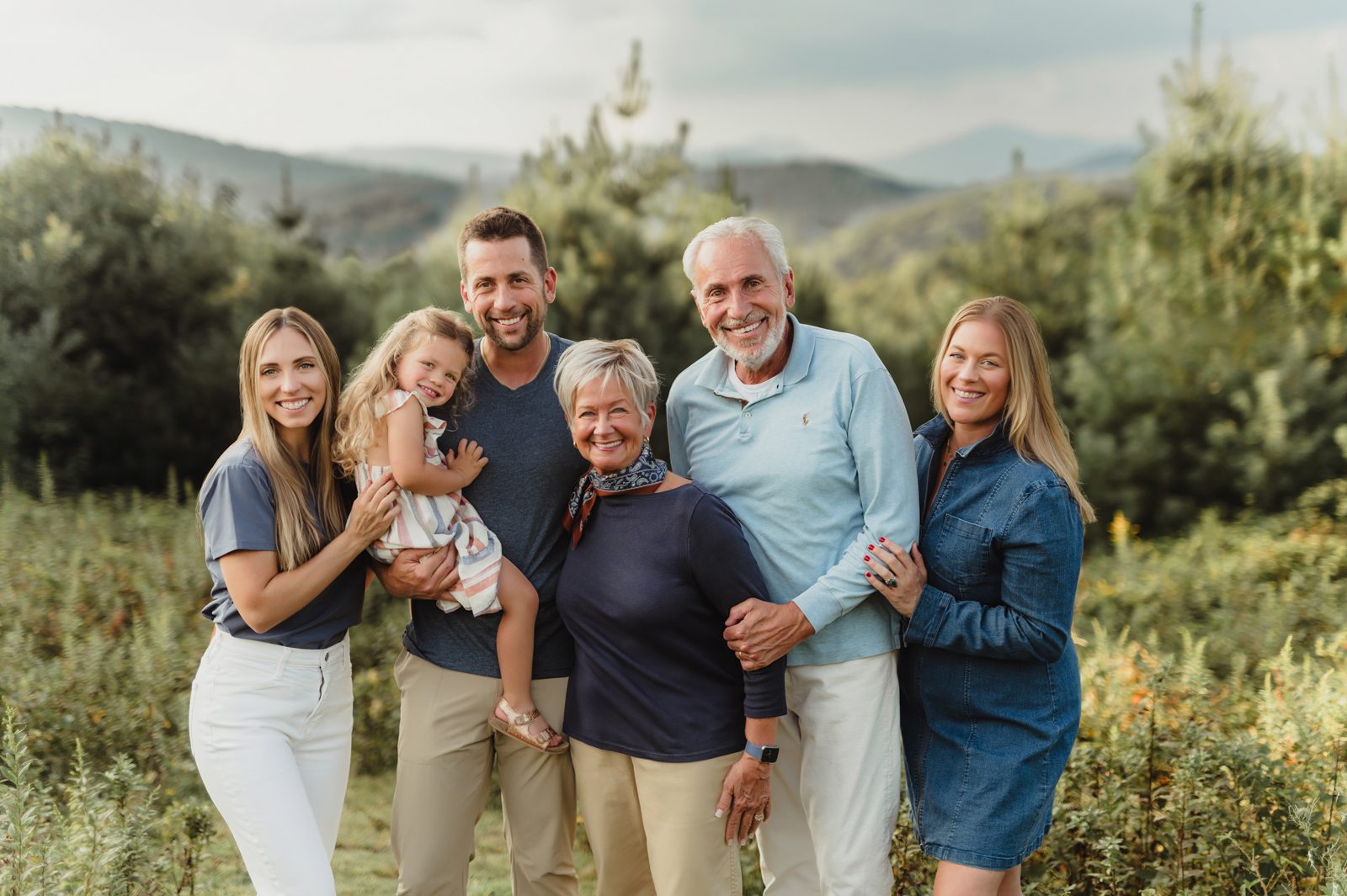 Capturing Generations: An Extended Family Photo Session in Blowing Rock-extended family photos in Blowing Rock Three-generation family smiling together during an extended family photo session in Blowing Rock, NC with the Blue Ridge Mountains in the background.