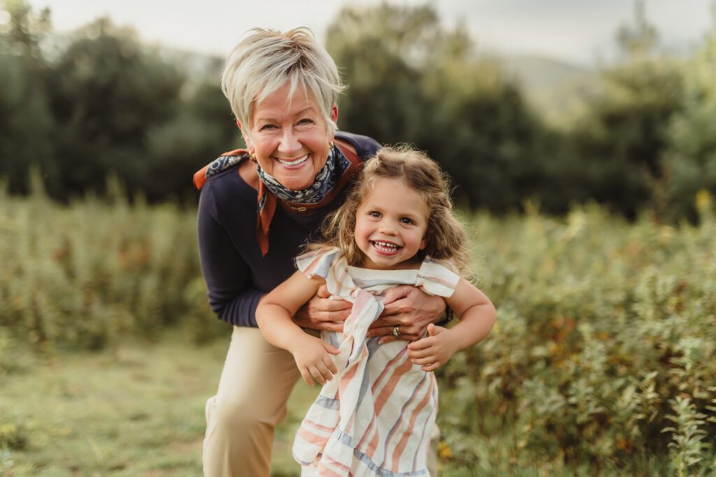 Capturing Generations: Extended Family Photos in Blowing Rock-extended family photos in Blowing Rock Grandmother playfully hugging her smiling granddaughter during an extended family photo session in the Blue Ridge Mountains near Blowing Rock, NC.