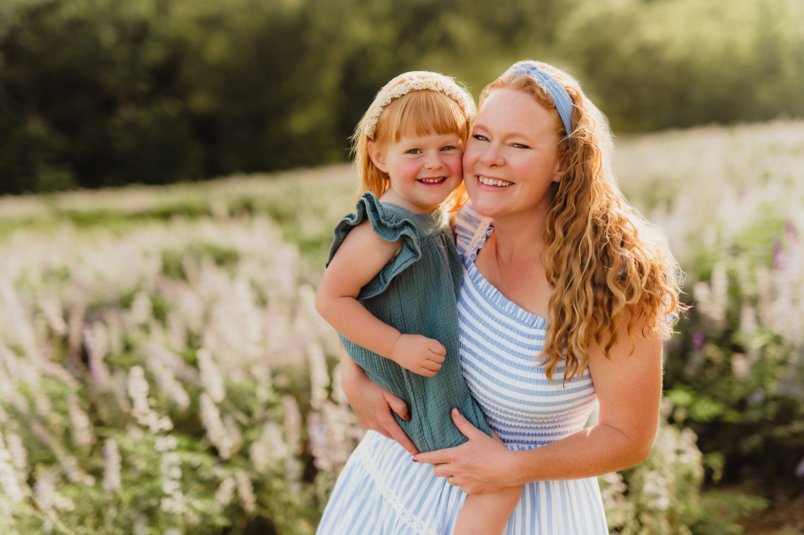 In Full Bloom: Mother Daughter Photos in a Field of Wildflowers-mother daughter photos Smiling mother and daughter with matching red hair posing together in a flower-filled field – Greensboro NC mother daughter photos