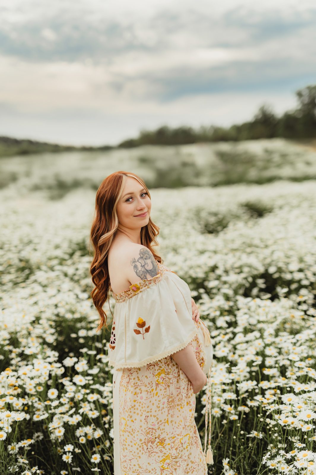 When to Take Maternity Photos (And Why It Matters!)-When to Take Maternity Photos Maternity photo in Greensboro NC of a pregnant woman in a Fillyboo dress standing in a wildflower field, taken by a Greensboro maternity photographer.