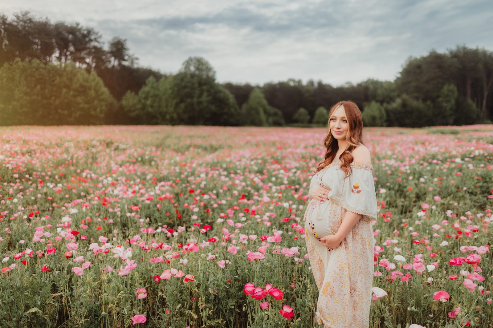 When to Take Maternity Photos (And Why It Matters!)-When to Take Maternity Photos When to take maternity photos: spring session in Greensboro NC with blooming flowers and golden light, featuring a pregnant woman in a floral dress.