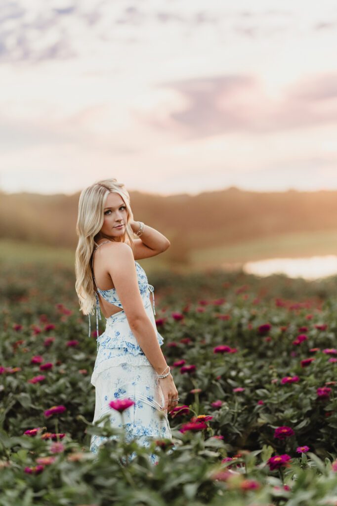 Senior photos in Winston-Salem sunflower field – natural pose with relaxed hand in hair at sunset