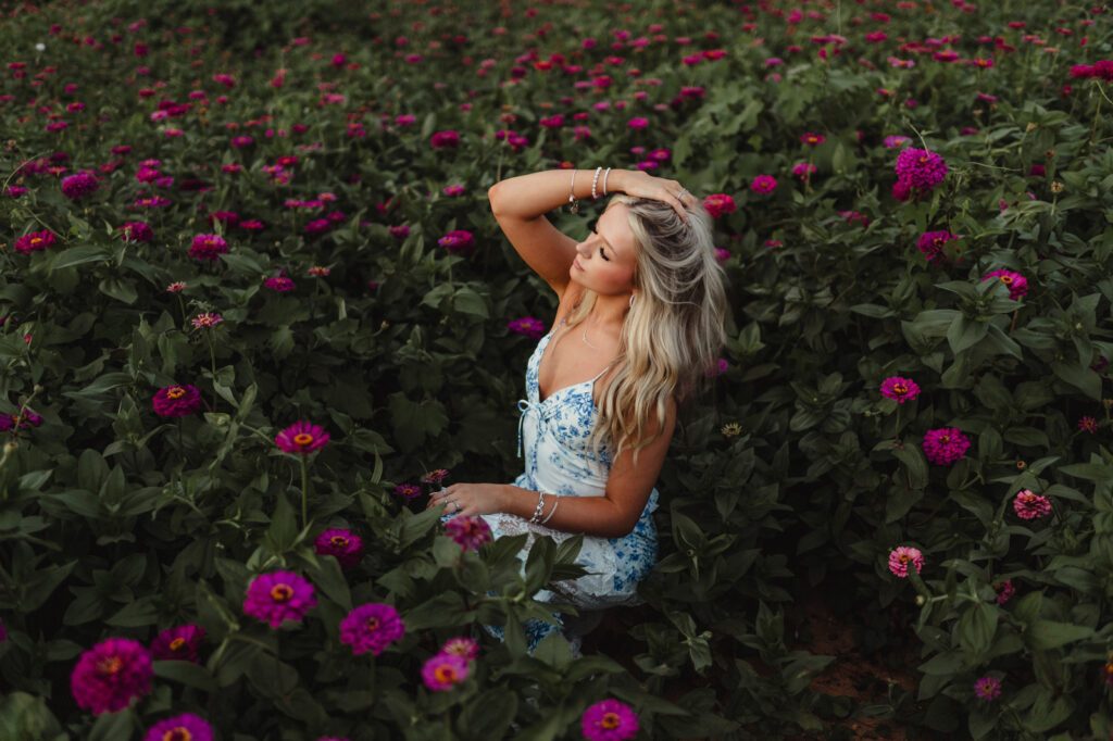 Triad NC senior photography – relaxed sitting pose in flower field with playful hand in hair