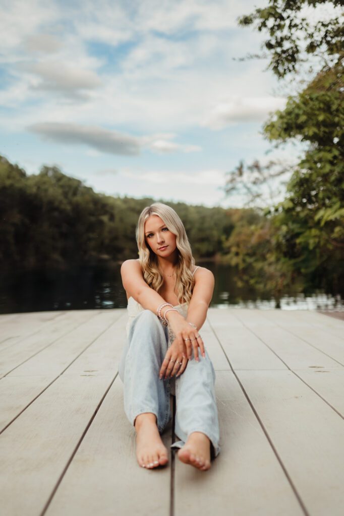 How to pose for senior pictures – relaxed sitting pose on dock, natural and confident senior portrait in High Point