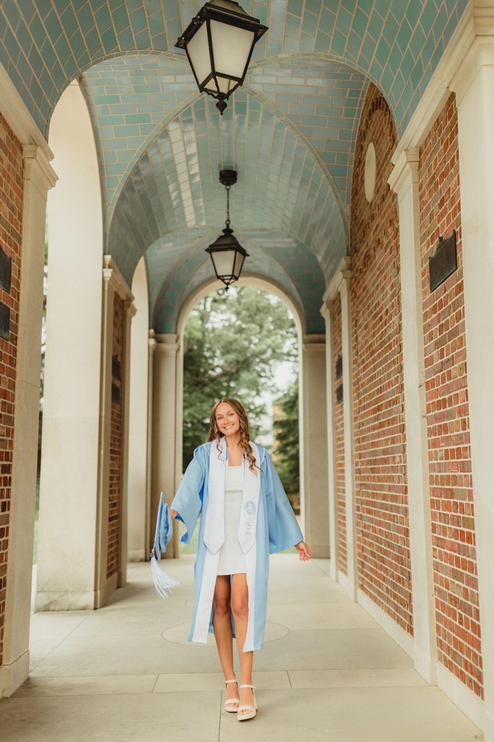 These UNC Graduation Photo Spots Still Feel Like Home-UNC Graduation Photos Detail shot of UNC grad in her gown holding her graduation cap at the base of the Bell Tower
