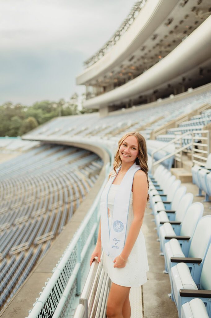 These UNC Graduation Photo Spots Still Feel Like Home-UNC Graduation Photos UNC Chapel Hill graduate standing in Kenan Stadium with stands in the background