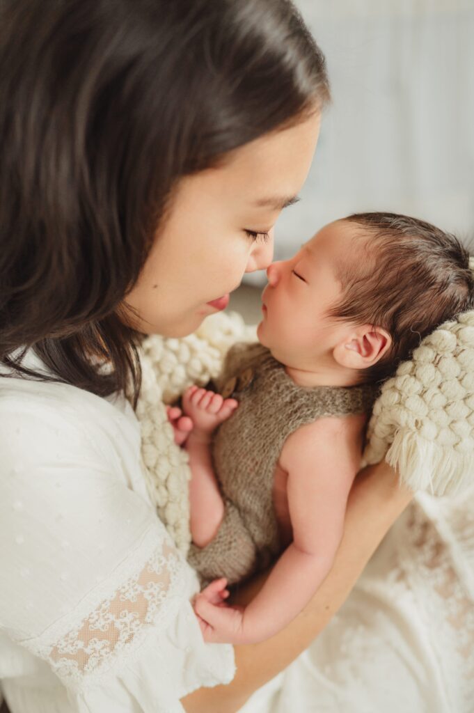 Mother and newborn baby touching noses during a lifestyle newborn photo session in Greensboro, NC.