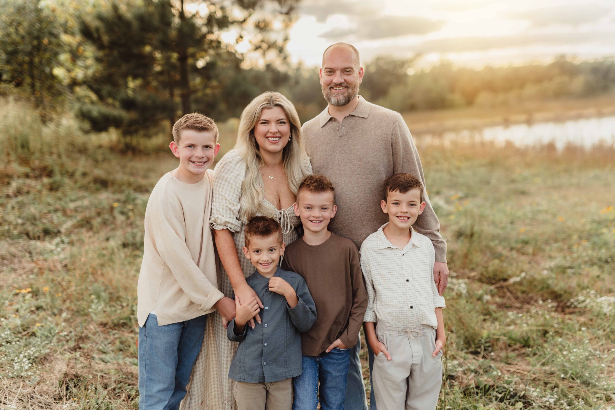The Wilson family posing together in soft, coordinated neutral fall outfits in a warm October field setting