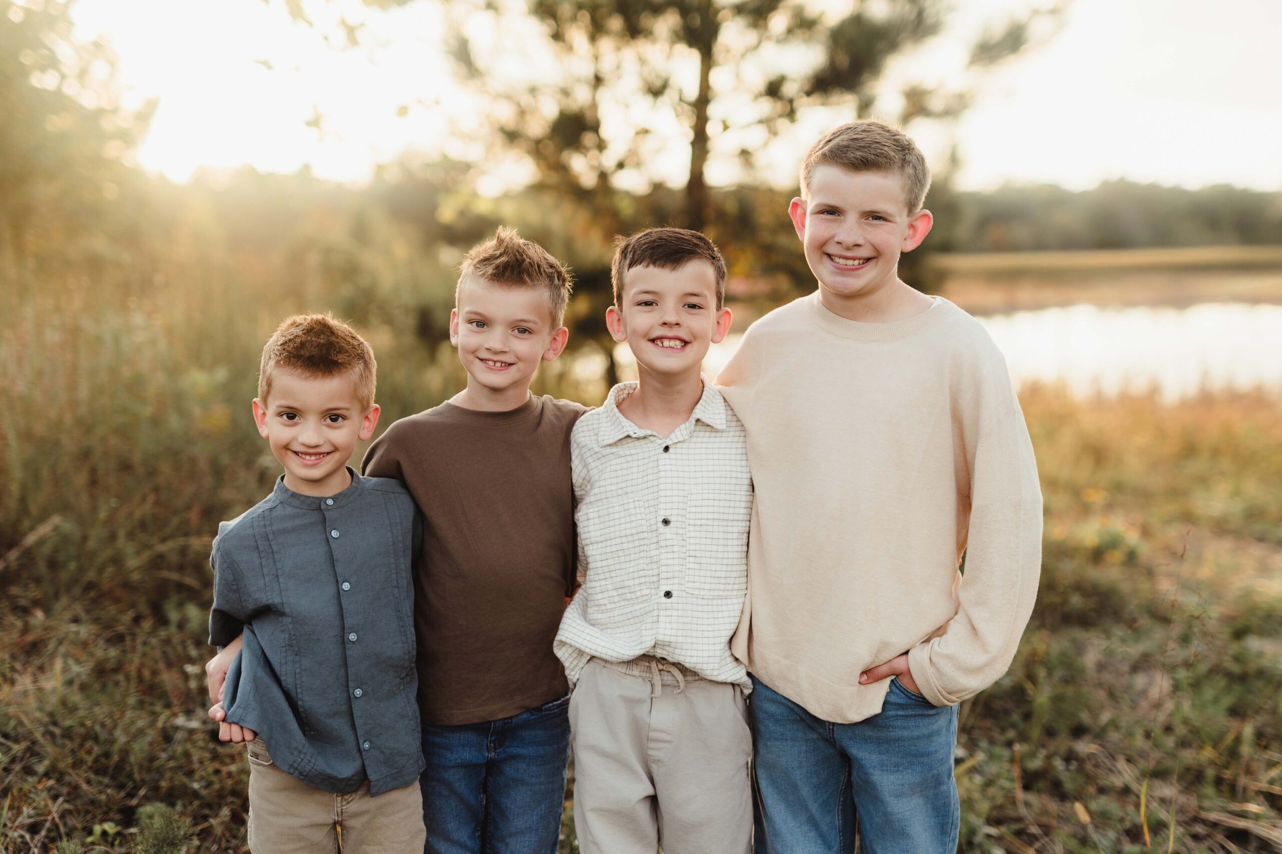 Four brothers smiling in the golden hour light, wearing soft earth tones and neutral fall clothing