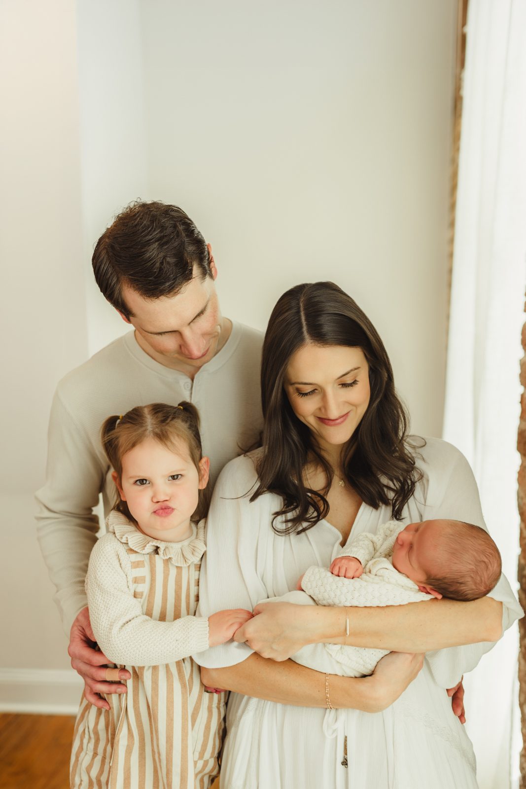 Greensboro newborn photography — big sister gives an epic pout while mom and dad beam down at sleeping newborn baby brother