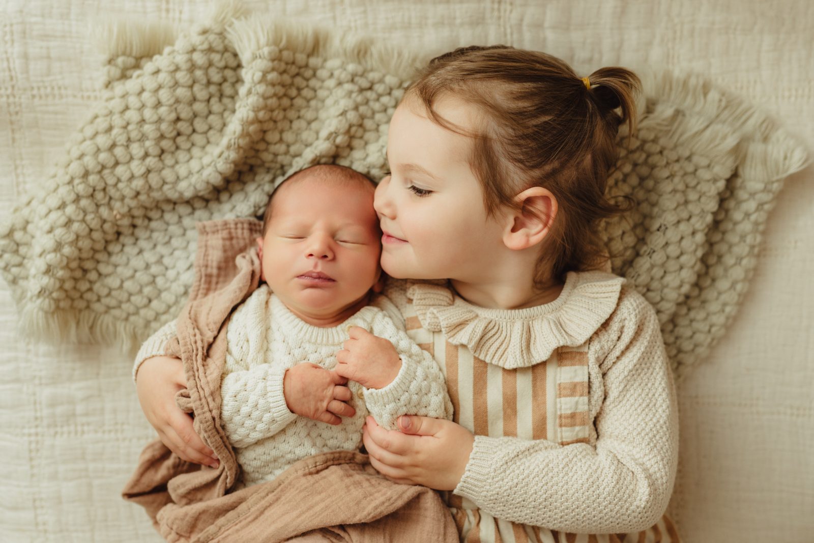 Big sister cuddles newborn baby brother at Greensboro newborn session at Revolution Mill