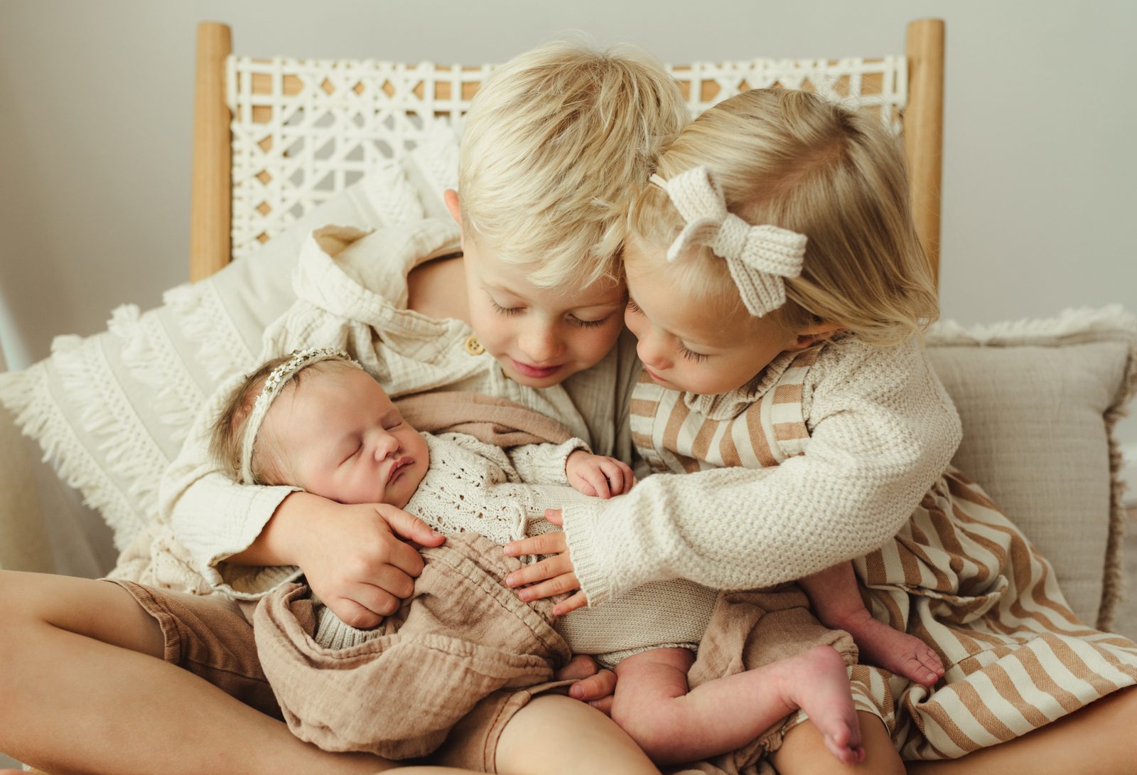Greensboro newborn photographer captures siblings holding baby sister in studio at Revolution Mill