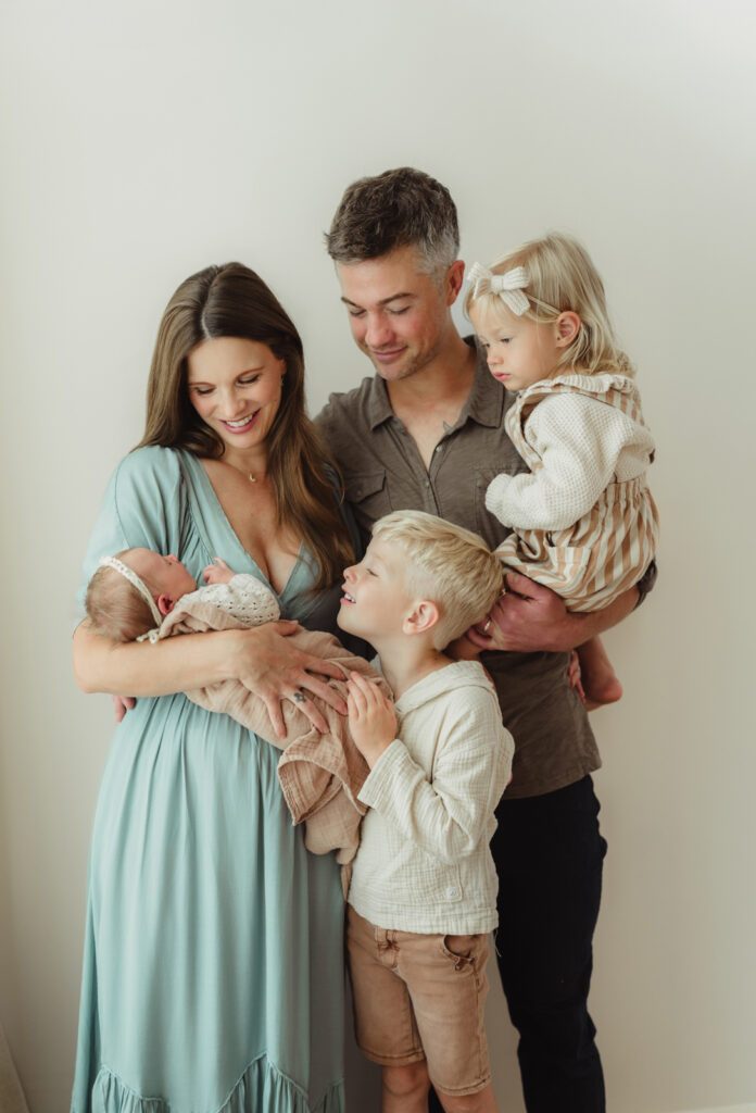 Lifestyle newborn photographer in Greensboro, NC captures family of five with newborn baby in studio session at Revolution Mill
