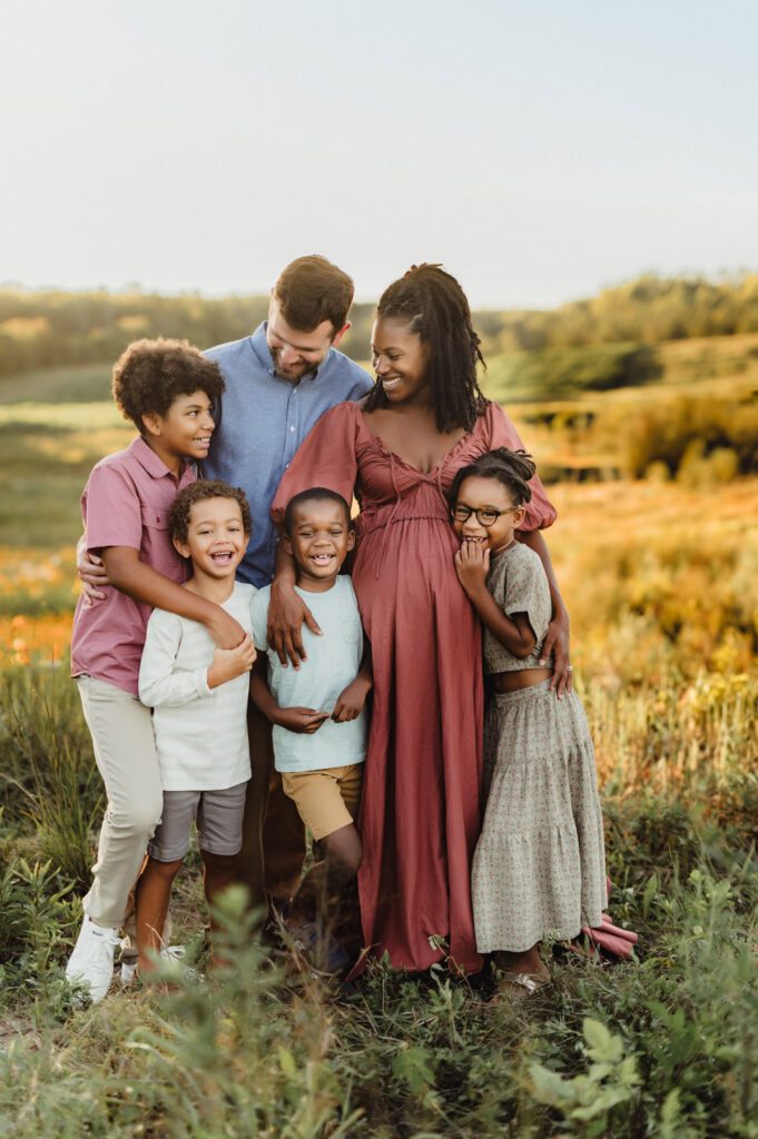 Family of six laughing together in a golden field during a Greensboro fall family photography session