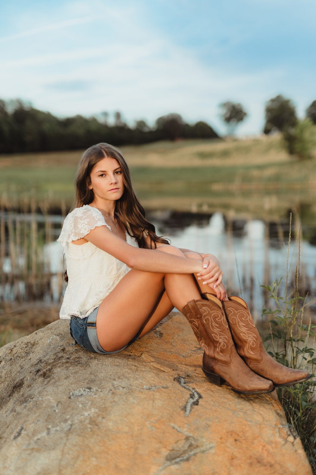 Greensboro senior photographer session on a lakeside rock at sunset