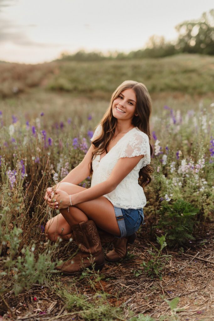 Senior girl squatting in a field of wildflowers near Greensboro