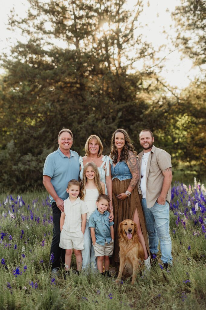 Worth the Drive: A Wake County Wildflower Session with the McInnes Family Three generations of a family with their golden retriever standing together in a field of larkspur