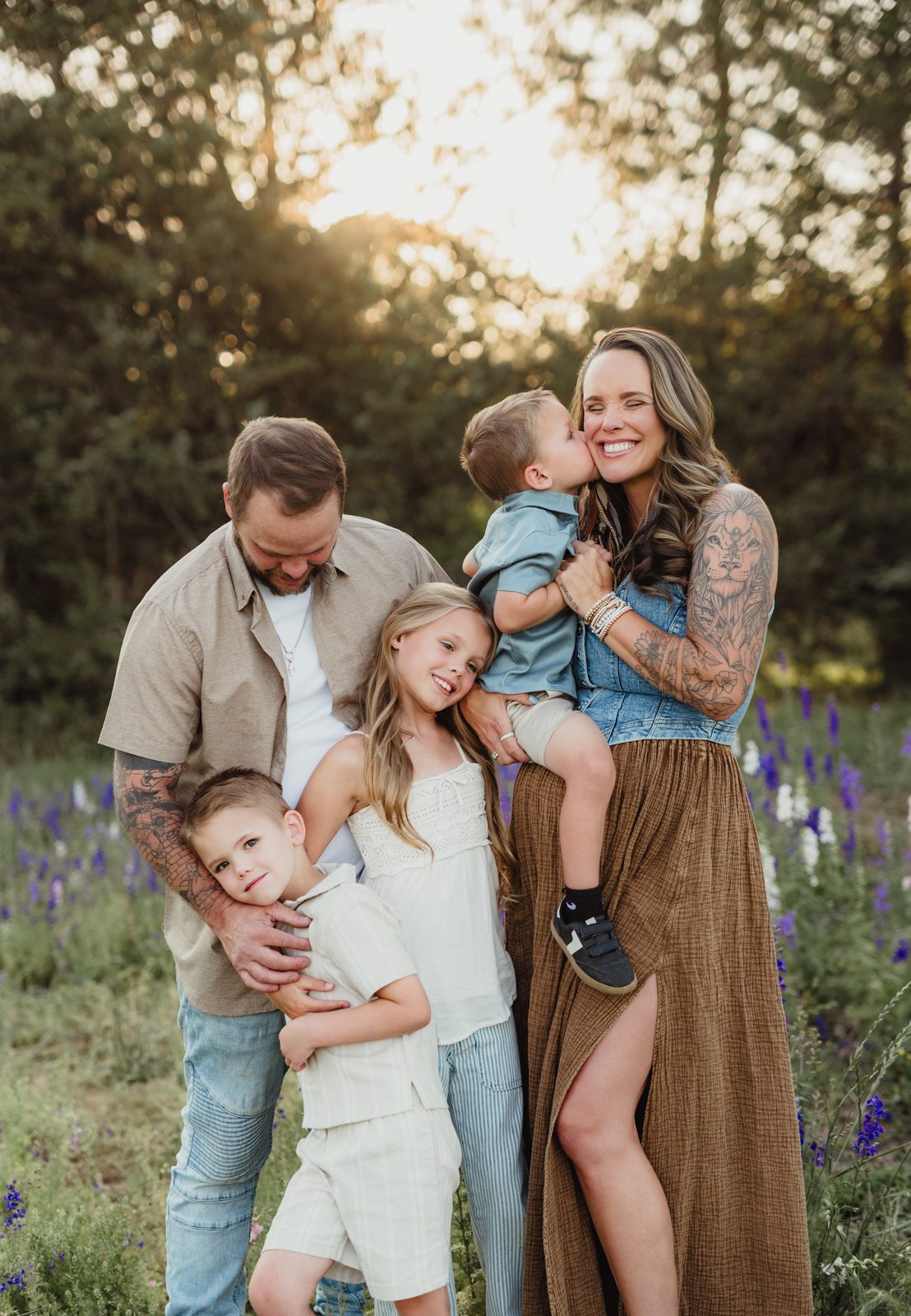 Worth the Drive: A Wake County Wildflower Session with the McInnes Family Dad and daughter close together while a toddler kisses his mom's cheek, family portrait in a larkspur field