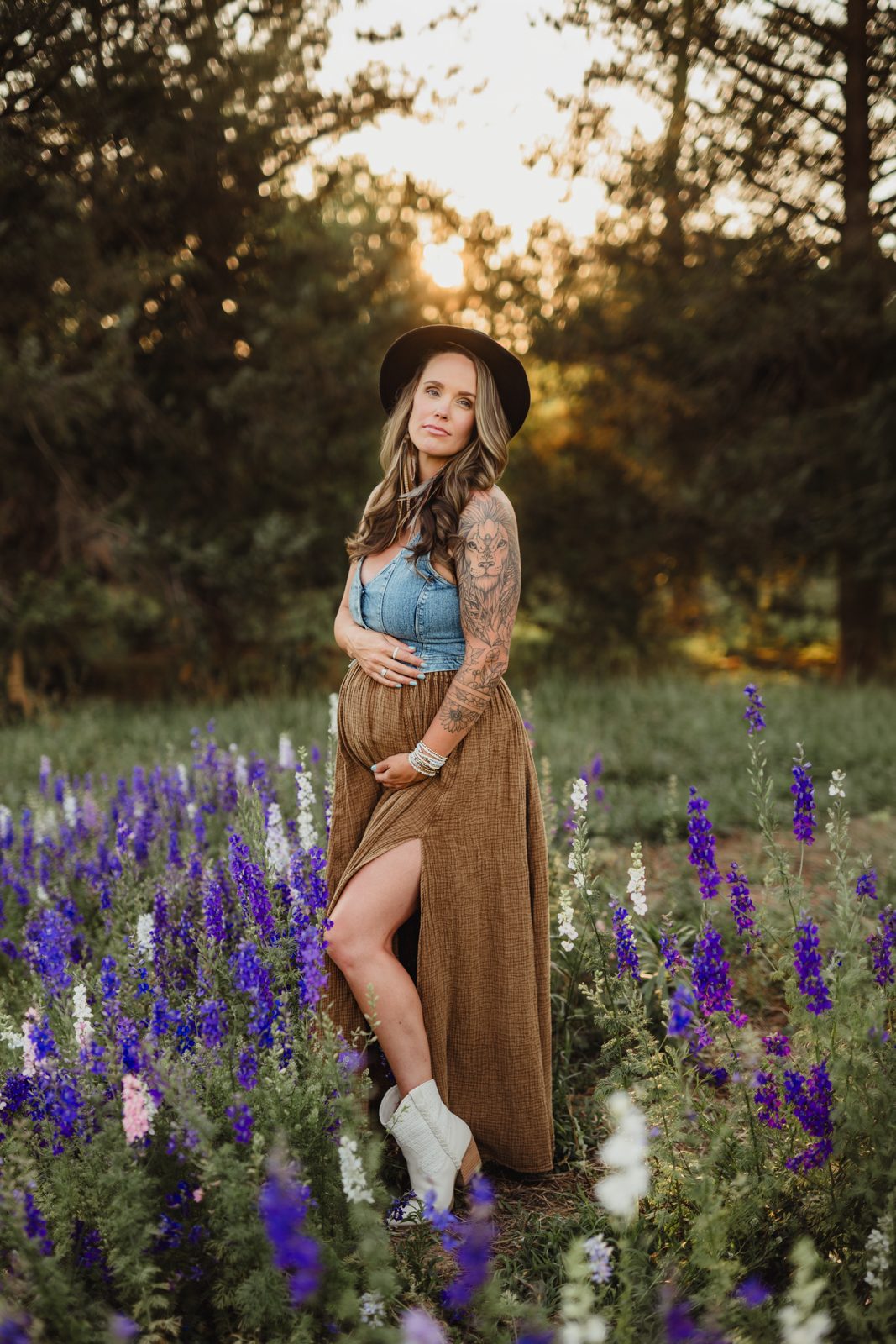 Worth the Drive: A Wake County Wildflower Session with the McInnes Family Pregnant mom in a black hat and white boots standing among purple and white larkspur at golden hour