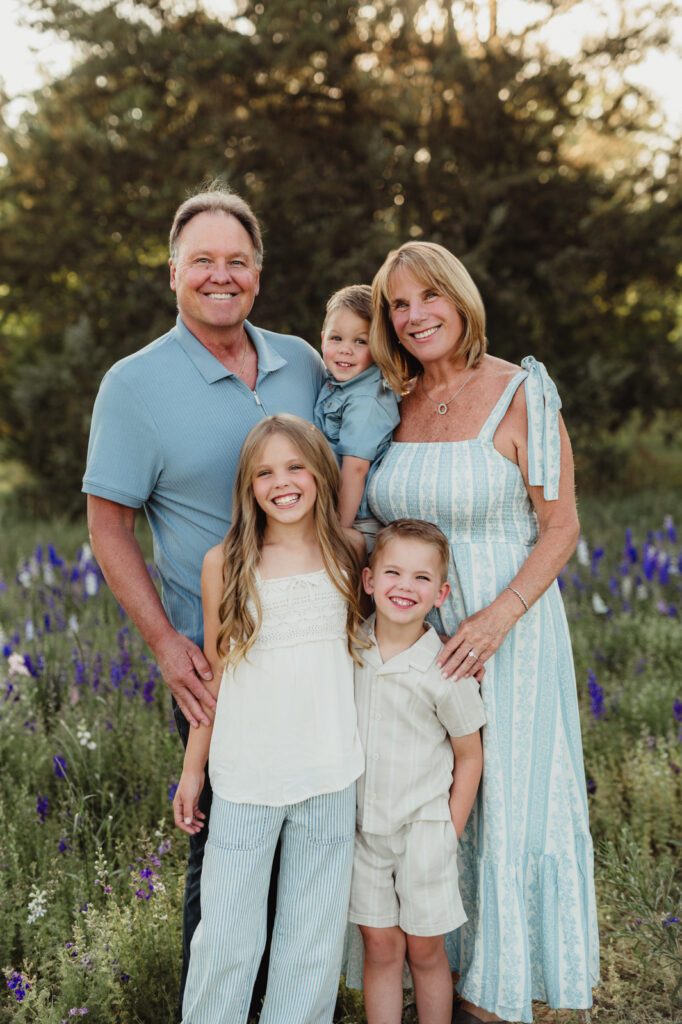 Worth the Drive: A Wake County Wildflower Session with the McInnes Family Grandparents smiling with their three grandchildren in a larkspur field near Raleigh, NC