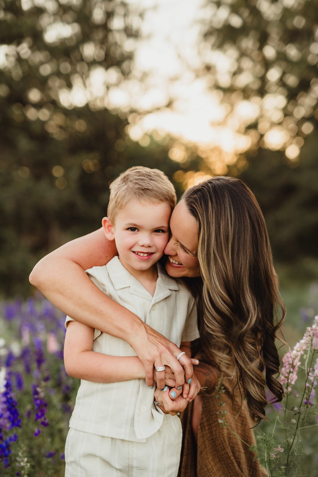 Worth the Drive: A Wake County Wildflower Session with the McInnes Family A mom embracing her son, foreheads close, hands clasped together in a larkspur field