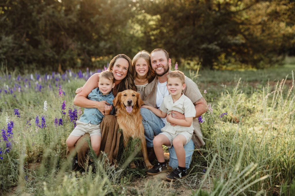 Worth the Drive: A Wake County Wildflower Session with the McInnes Family A family and their golden retriever smiling together in a Wake County wildflower field